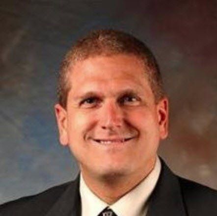 A man in a suit and tie is smiling for the camera.