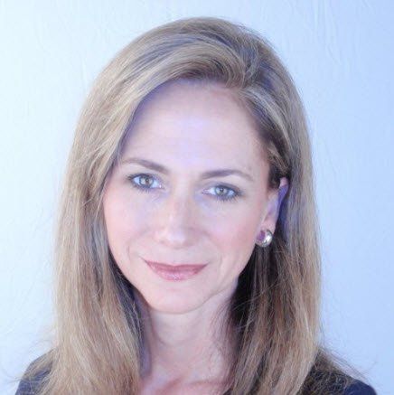 A woman with long blonde hair and earrings is smiling for the camera.