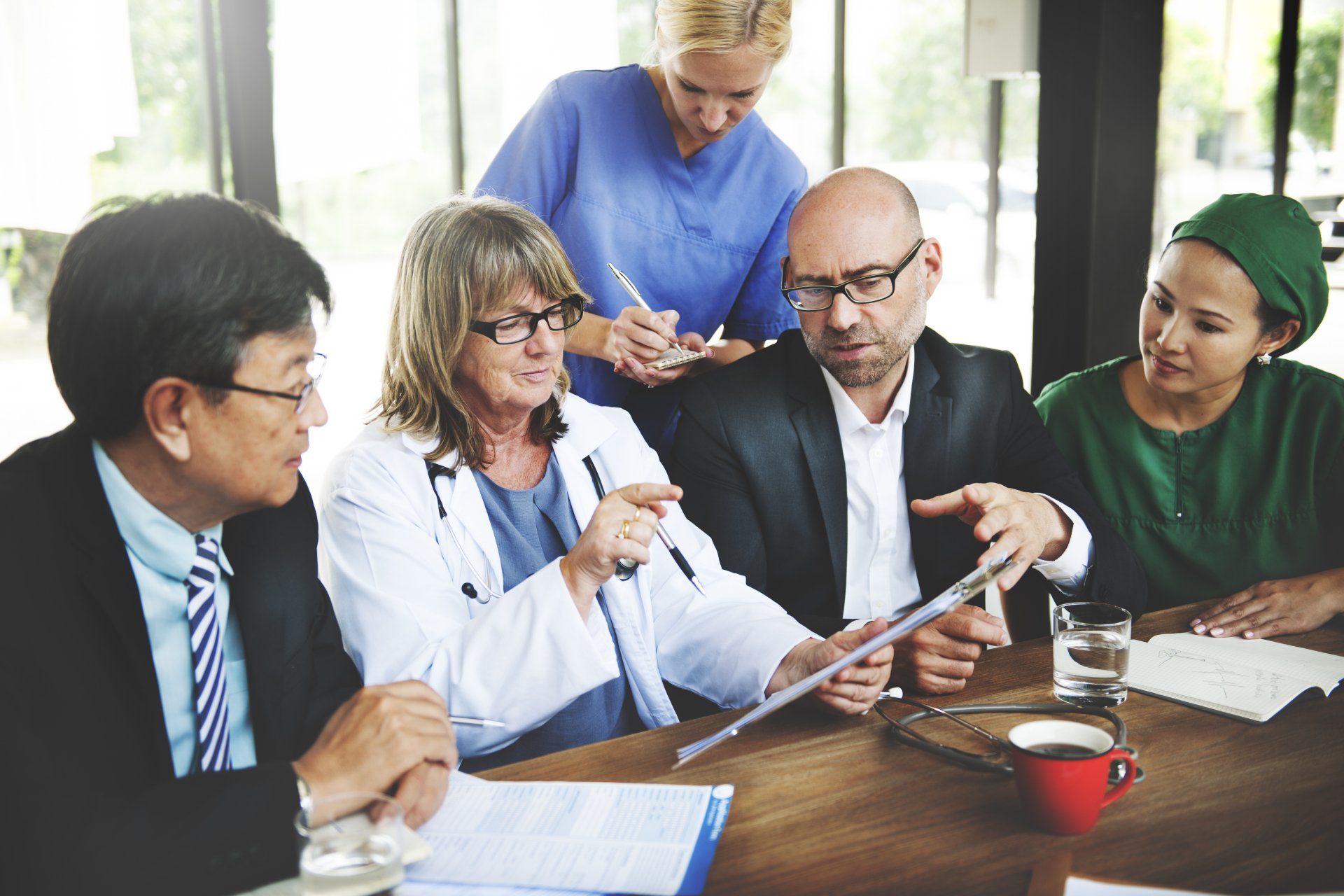 A group of doctors and nurses are sitting around a table having a meeting.