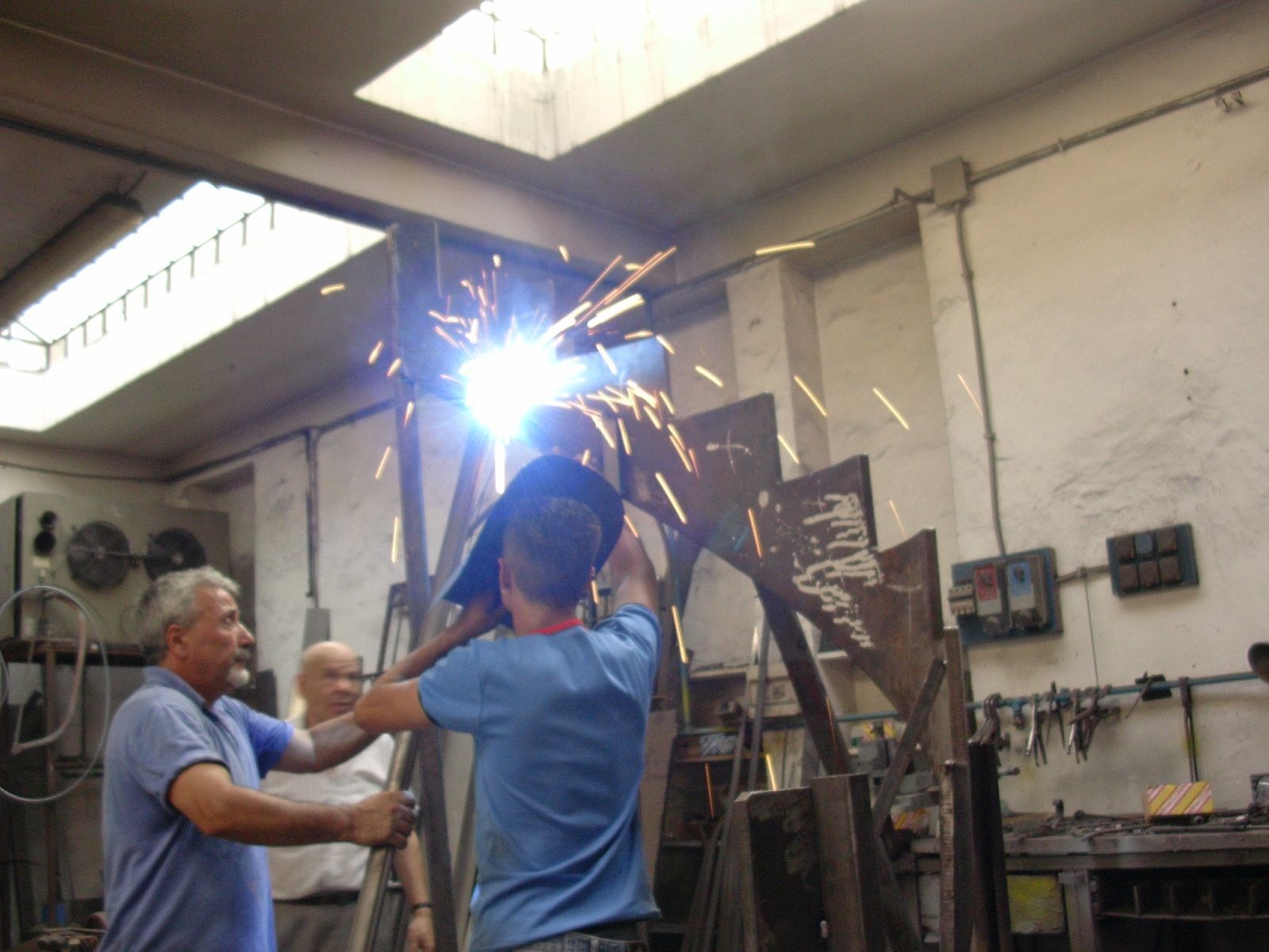 Un uomo con una camicia blu sta saldando un pezzo di metallo