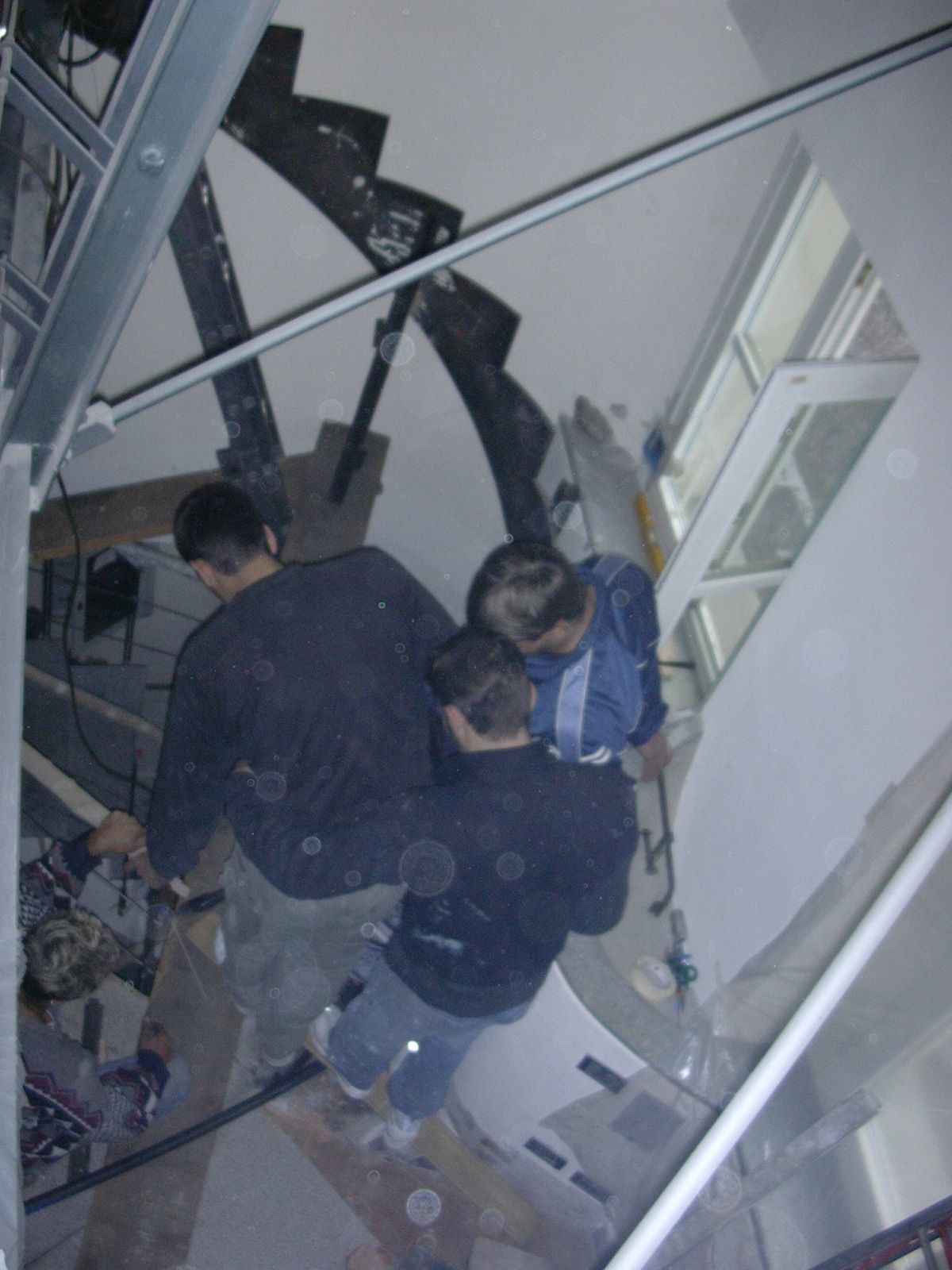 Un gruppo di persone in piedi in una stanza con una scala sullo sfondo