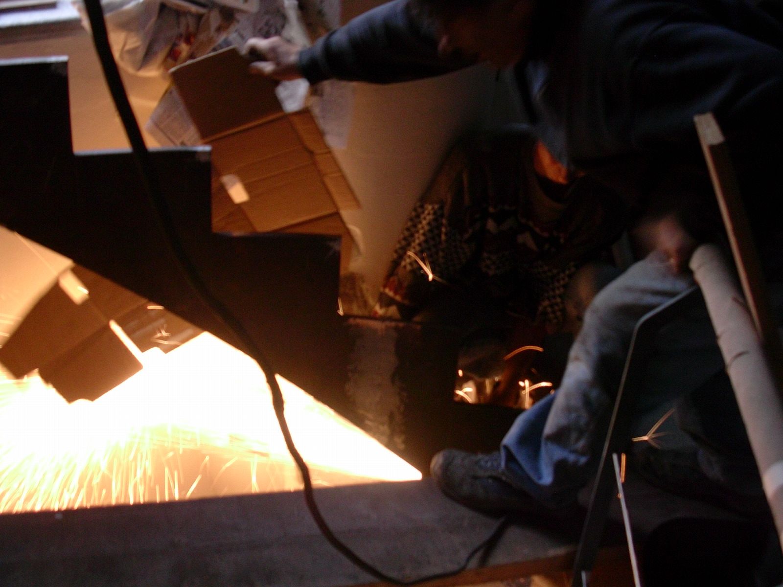 Un uomo sta saldando un pezzo di metallo da cui escono delle scintille