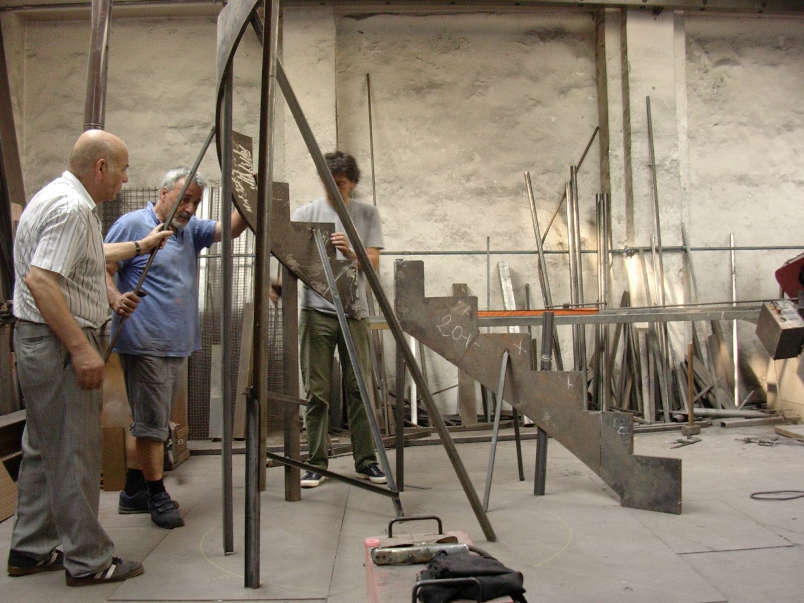 Tre uomini stanno lavorando su una scala di metallo in una fabbrica
