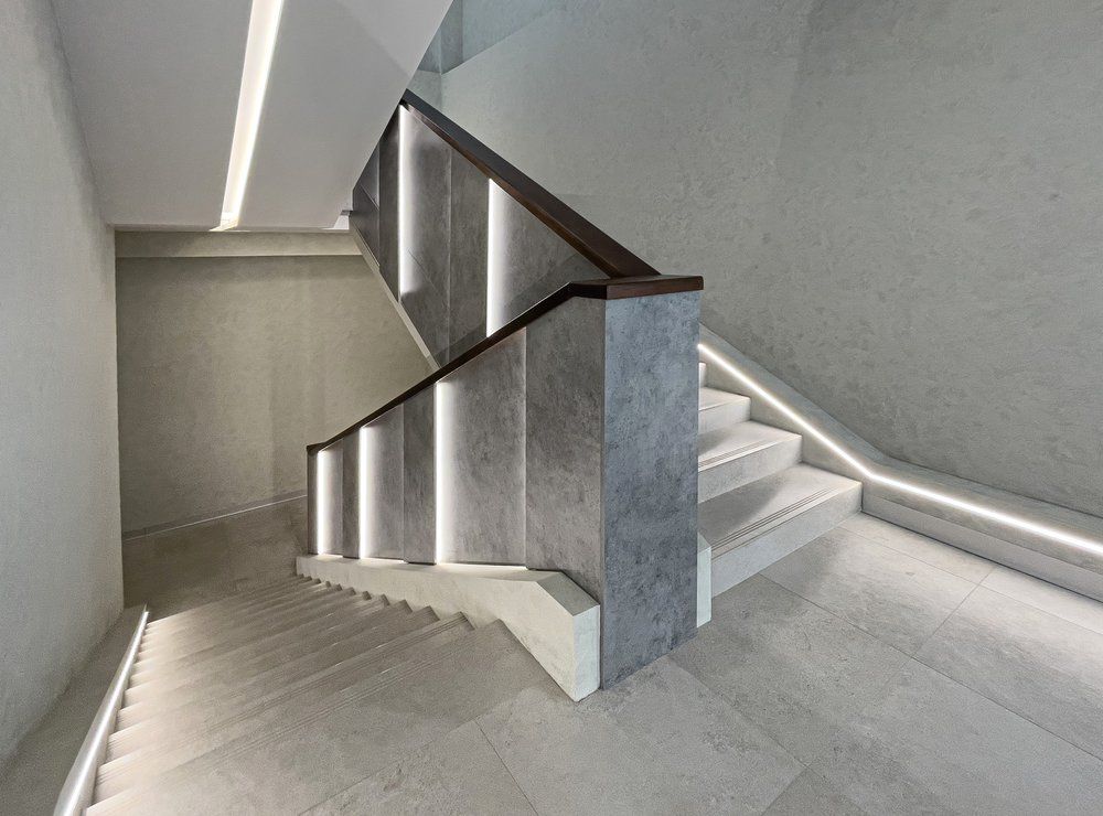 Un escalier avec une rampe en bois et des lumières au mur.