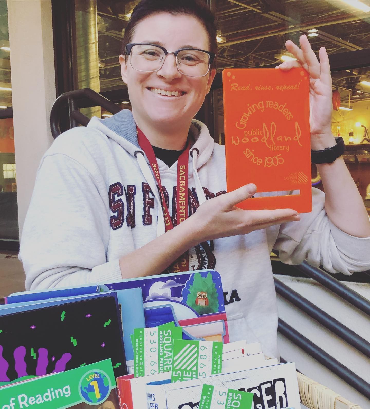 A woman wearing a sweatshirt that says ' virginia ' on it is holding a book