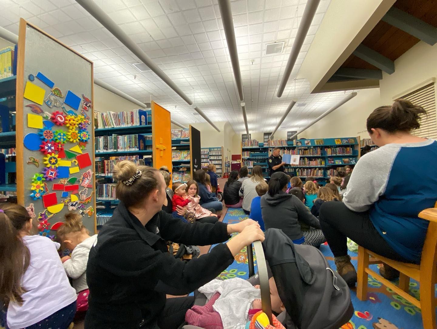 A group of people are sitting on the floor in a library.