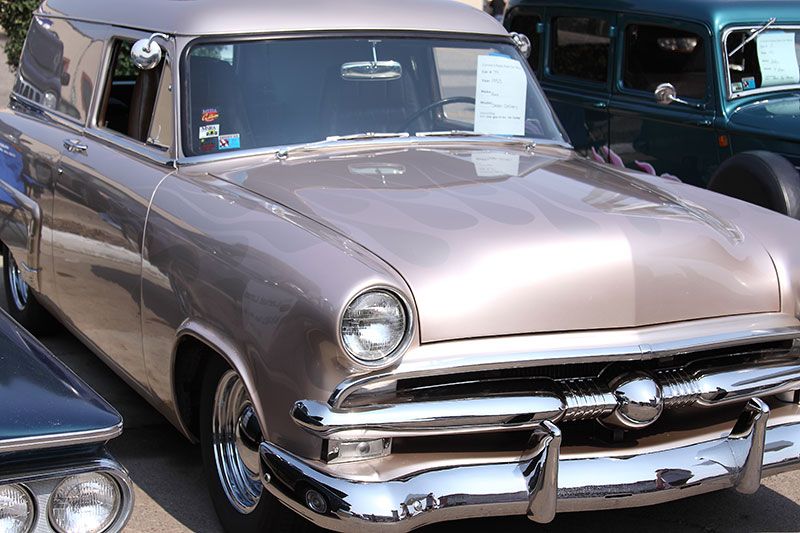A very old car is parked next to another car.