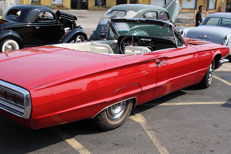 A red convertible is parked in a parking lot.