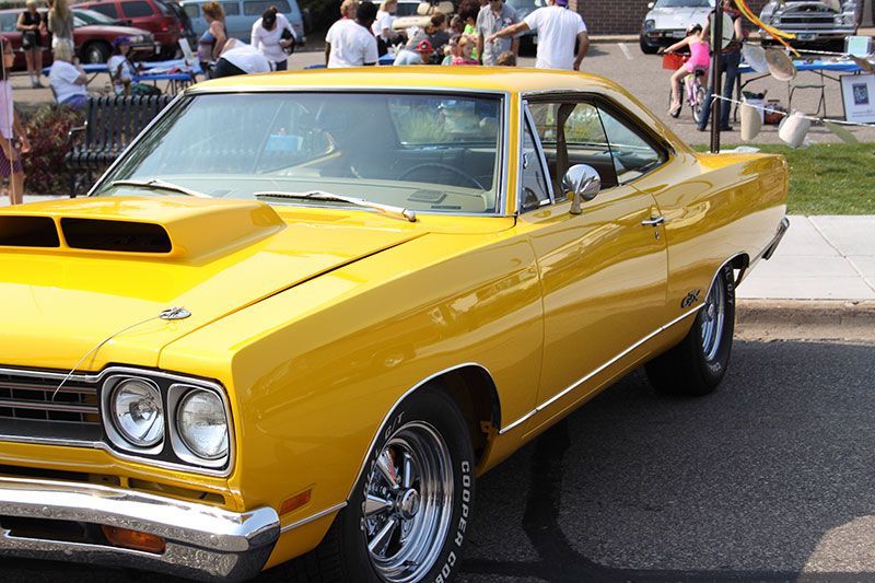 A yellow car with a hood scoop is parked on the side of the road.