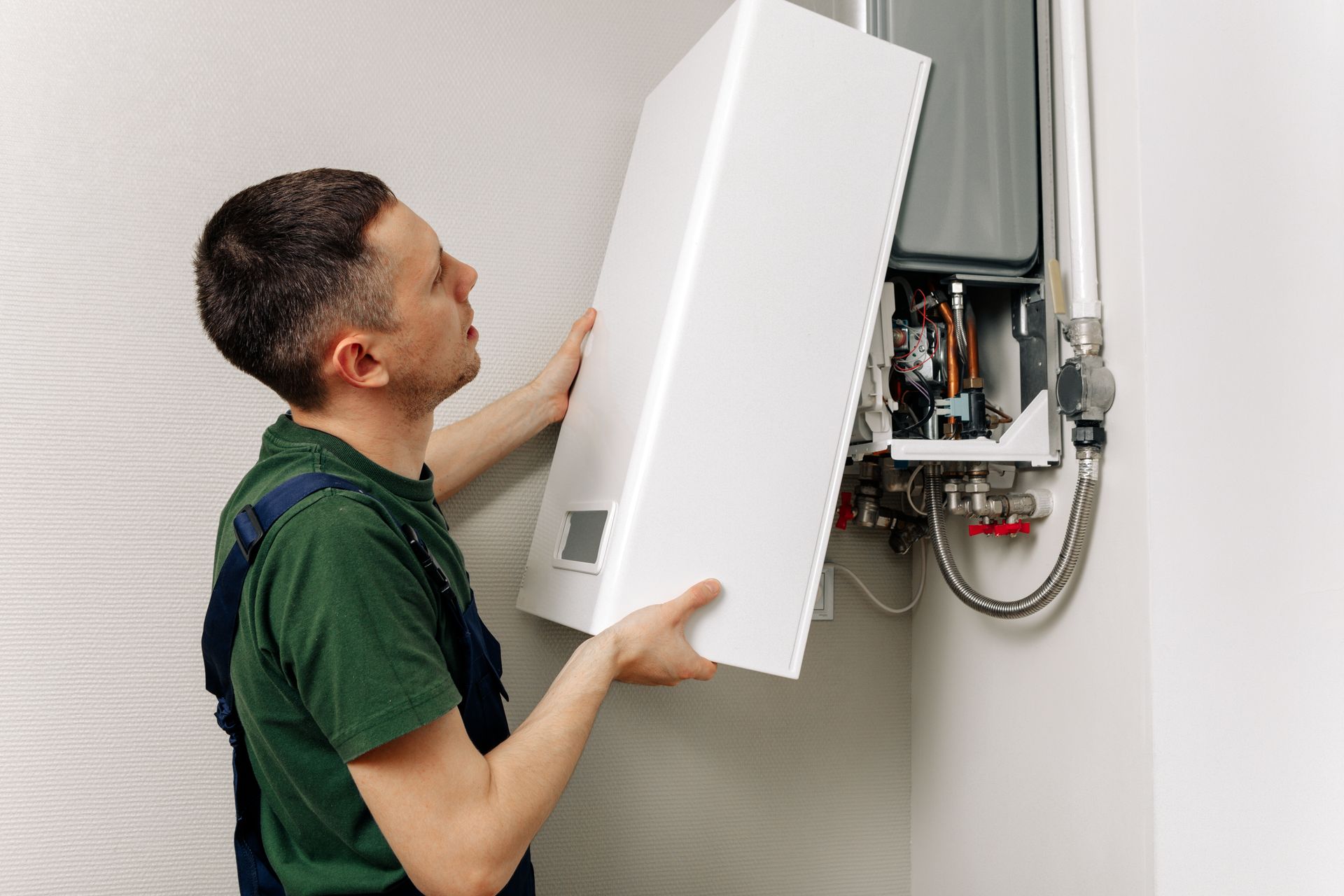 A man is installing a boiler on a wall.