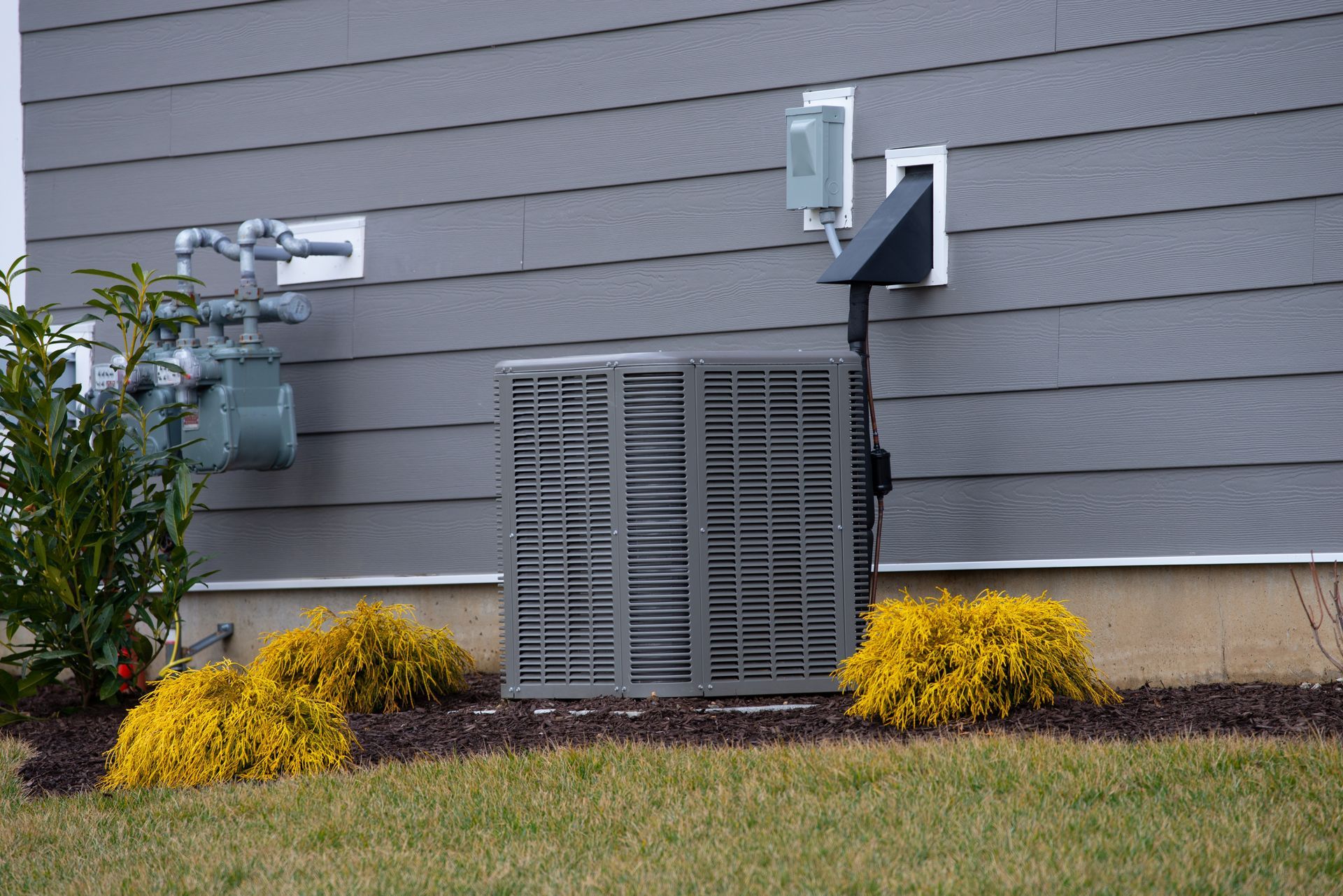 An air conditioner is sitting on the side of a house.