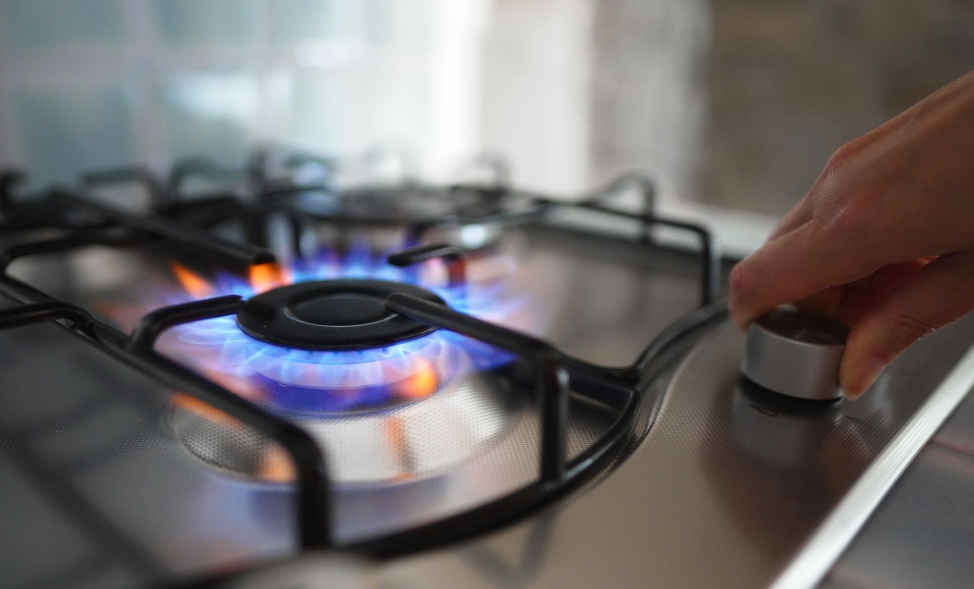 A person is turning the gas burner on a stove.