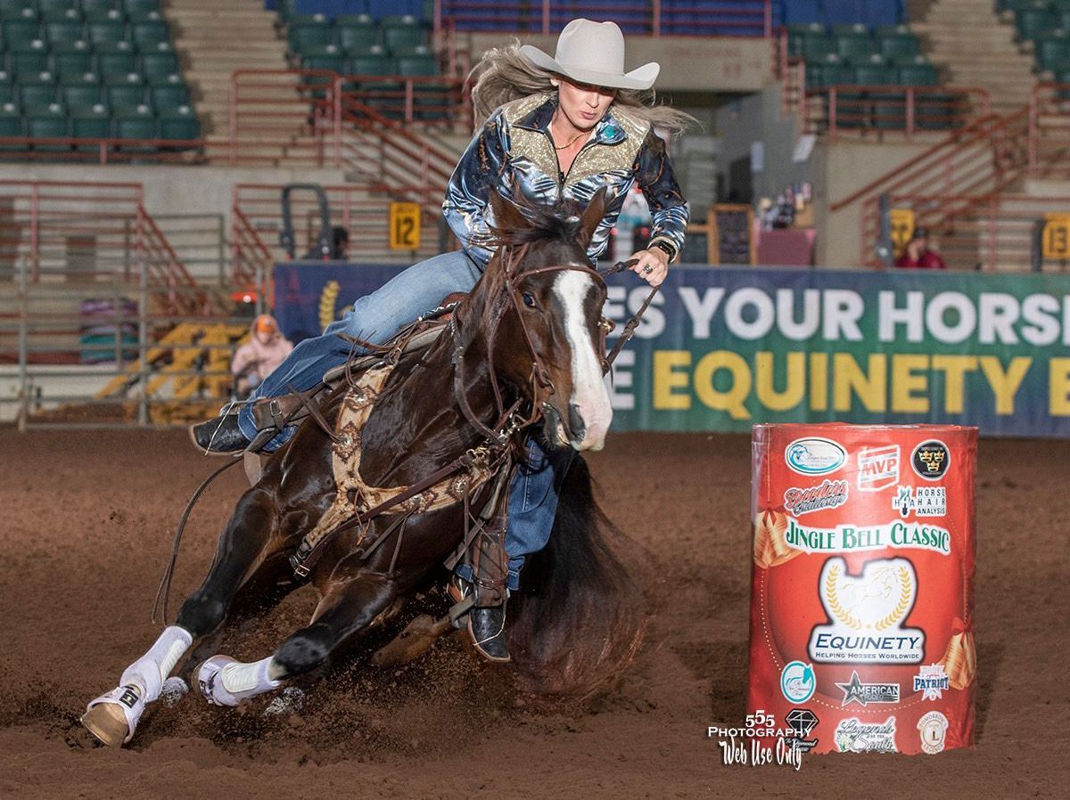 A woman is riding a horse in front of a sign that says