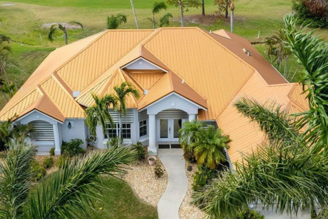 House with orange tile roof, light blue walls, and palm trees.
