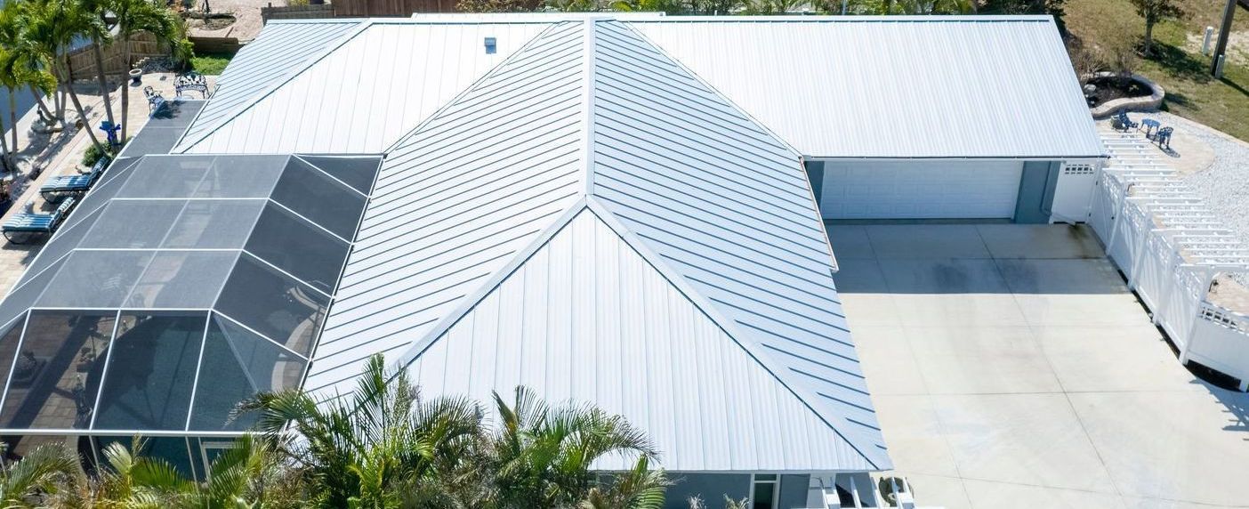 Overhead view of a modern house with a white roof and a screened-in pool.