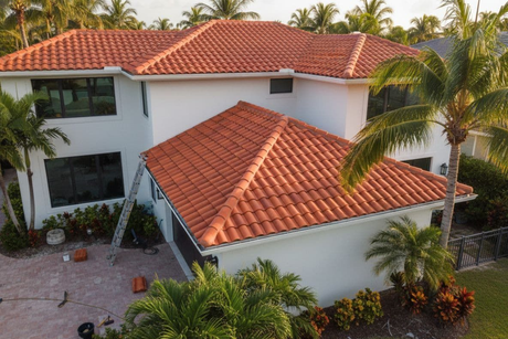 Aerial view of a house with a light-colored roof.  The roof has multiple gabled sections.