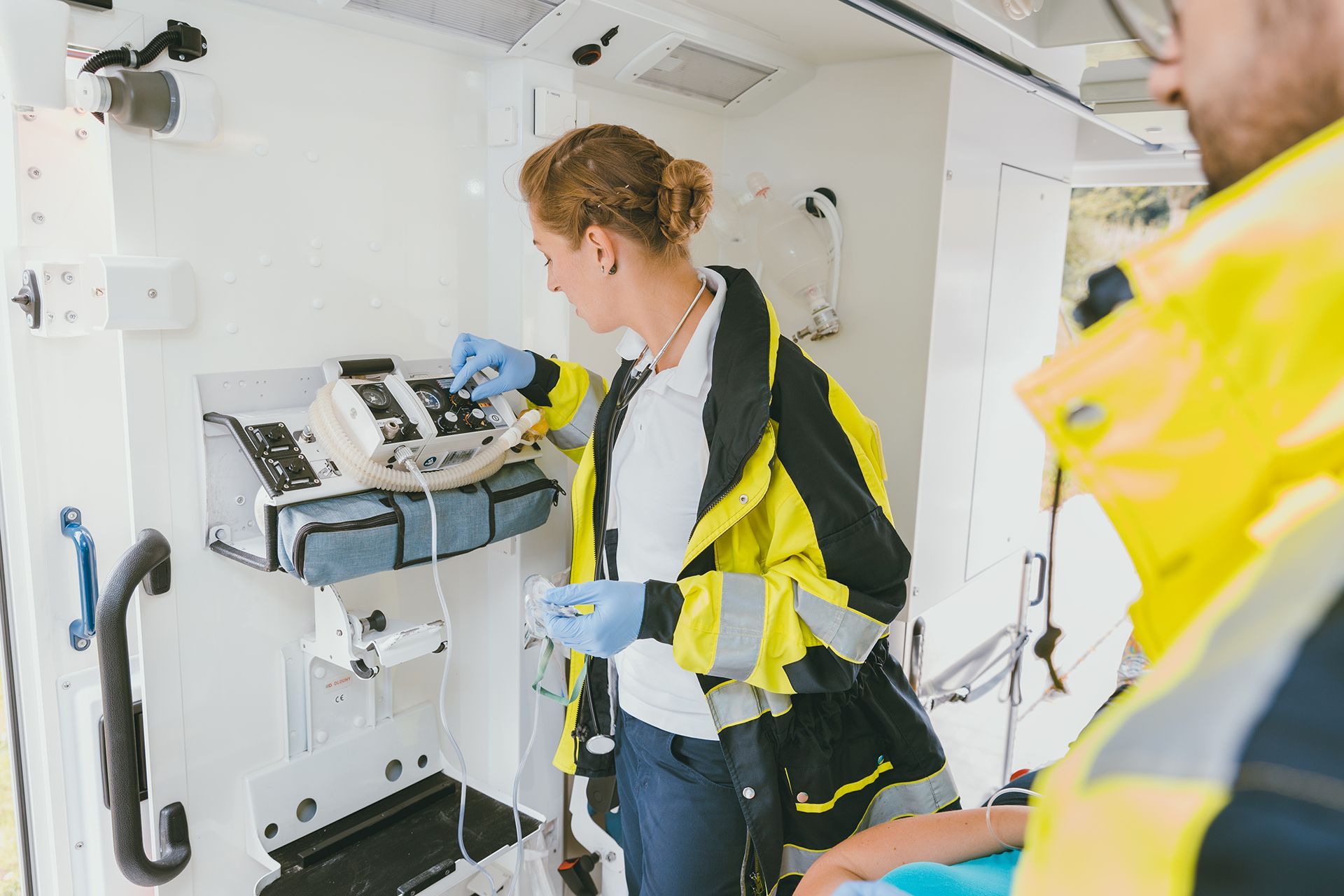 Emergency medical technician in ambulance adjusting medical equipment.