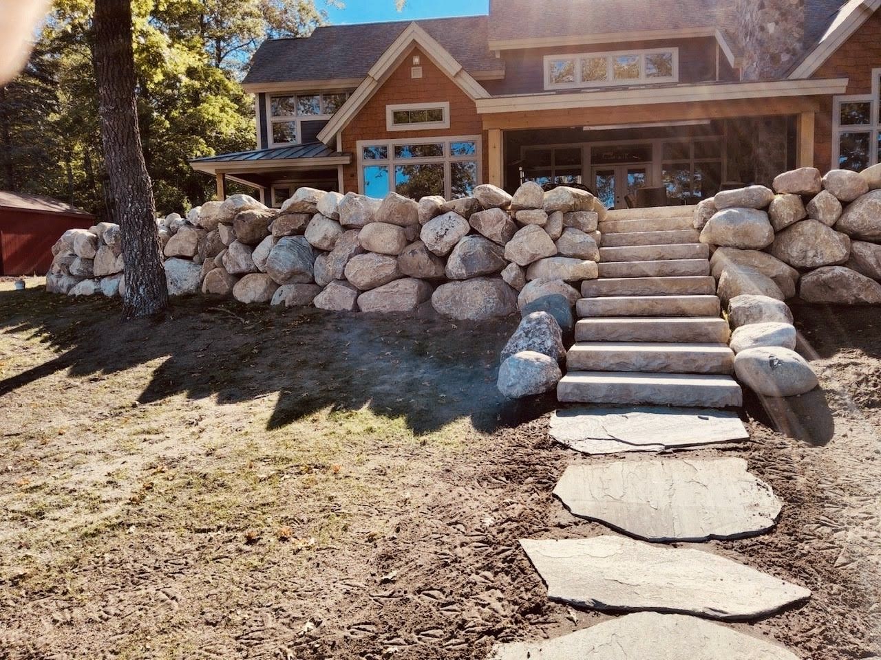 A house with a stone wall and stairs leading up to it