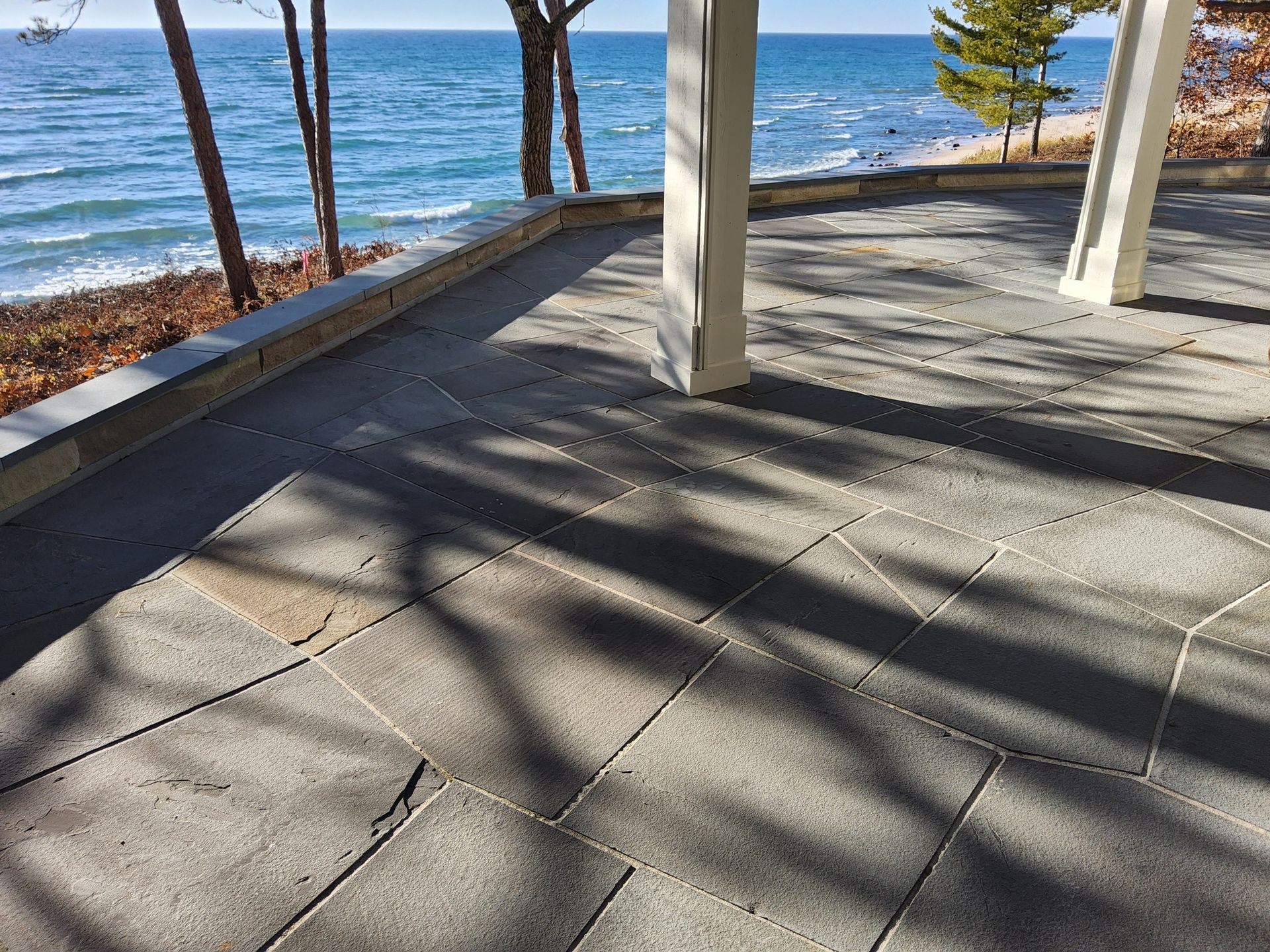 A patio with a view of the ocean and trees.