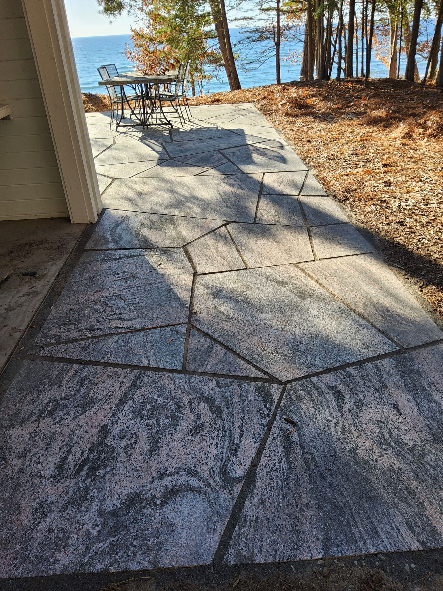 A patio with a table and chairs next to a body of water.
