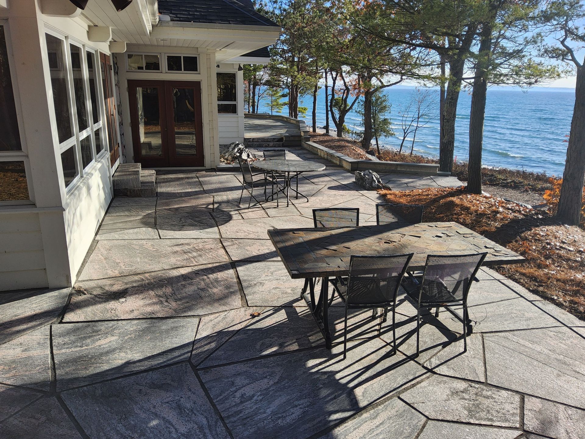 A patio with a table and chairs next to a house with a view of the ocean.