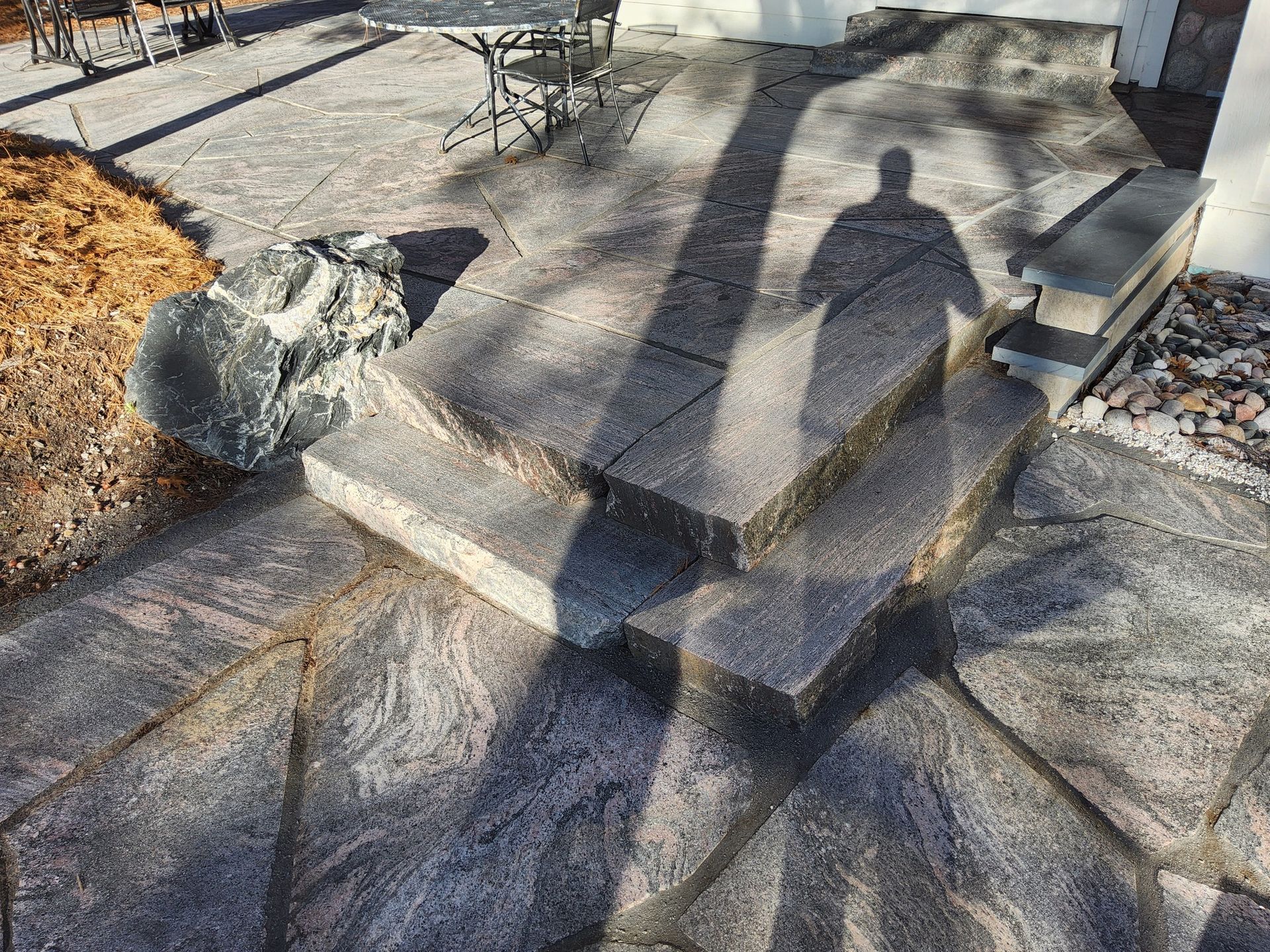 A shadow of a person is cast on a stone patio.