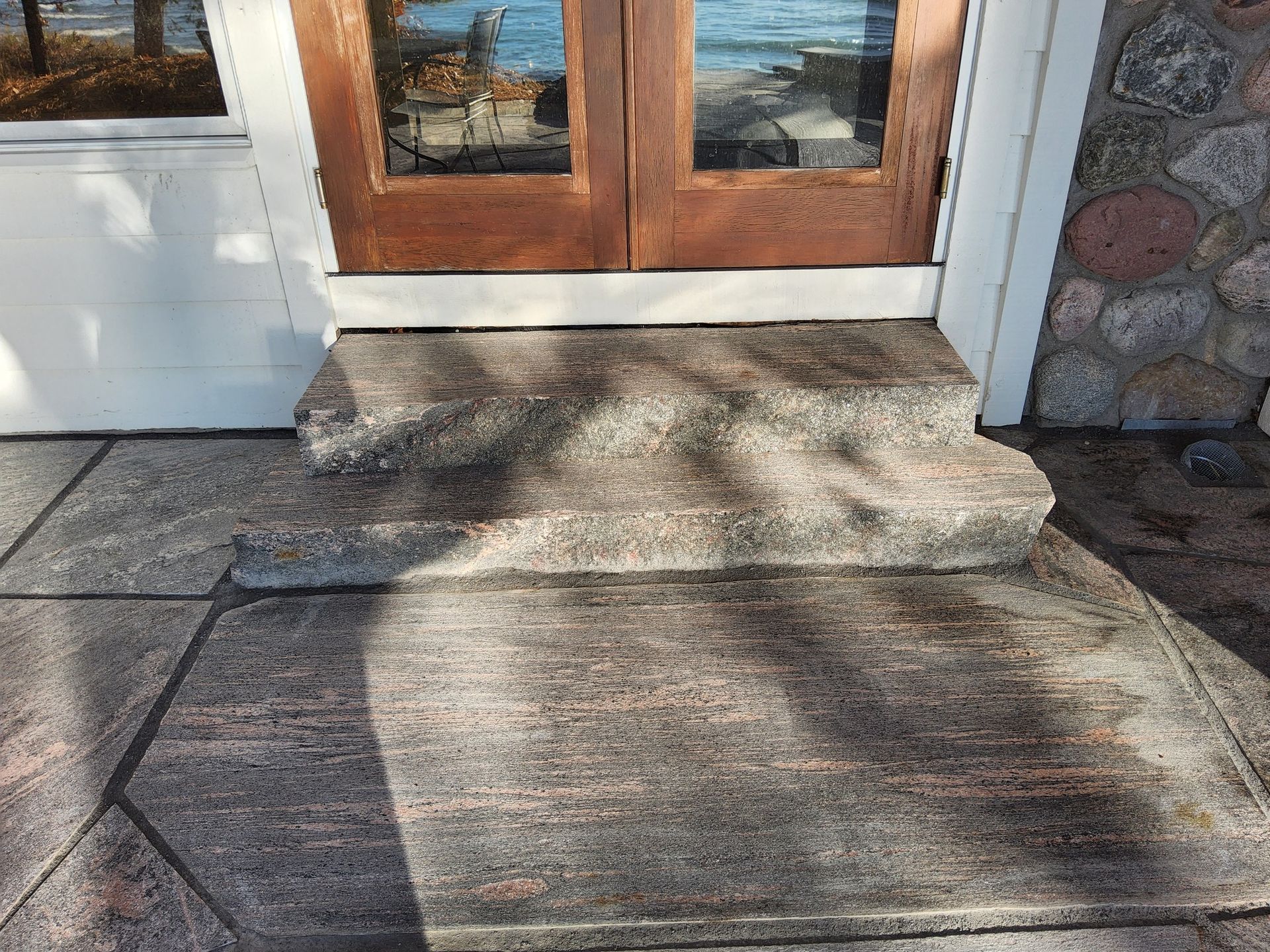 A stone walkway leading to a wooden door with steps leading up to it.