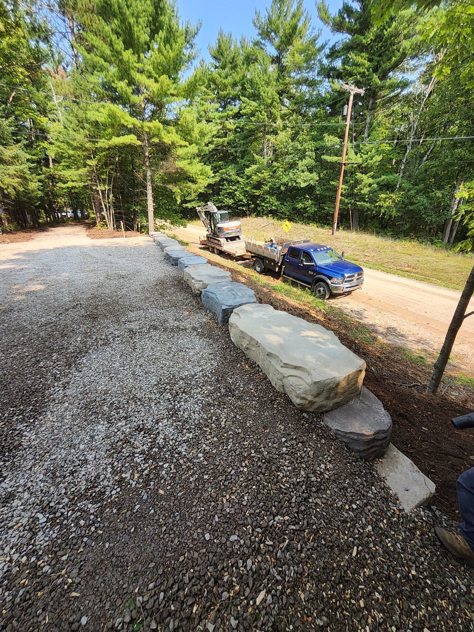 A blue truck is parked on the side of a gravel road.