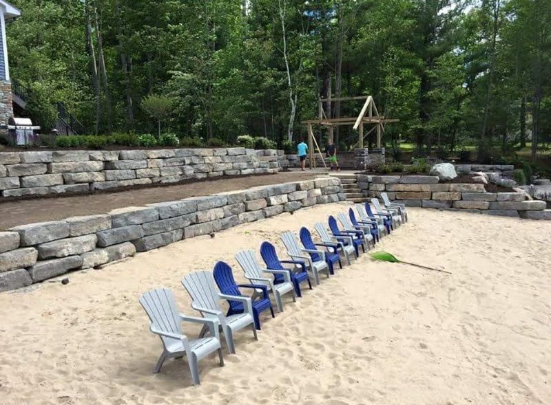 A row of chairs are lined up on a sandy beach.