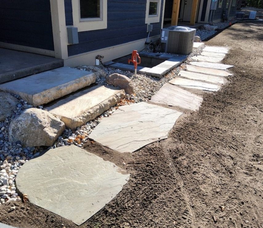 A stone walkway is being built in front of a house