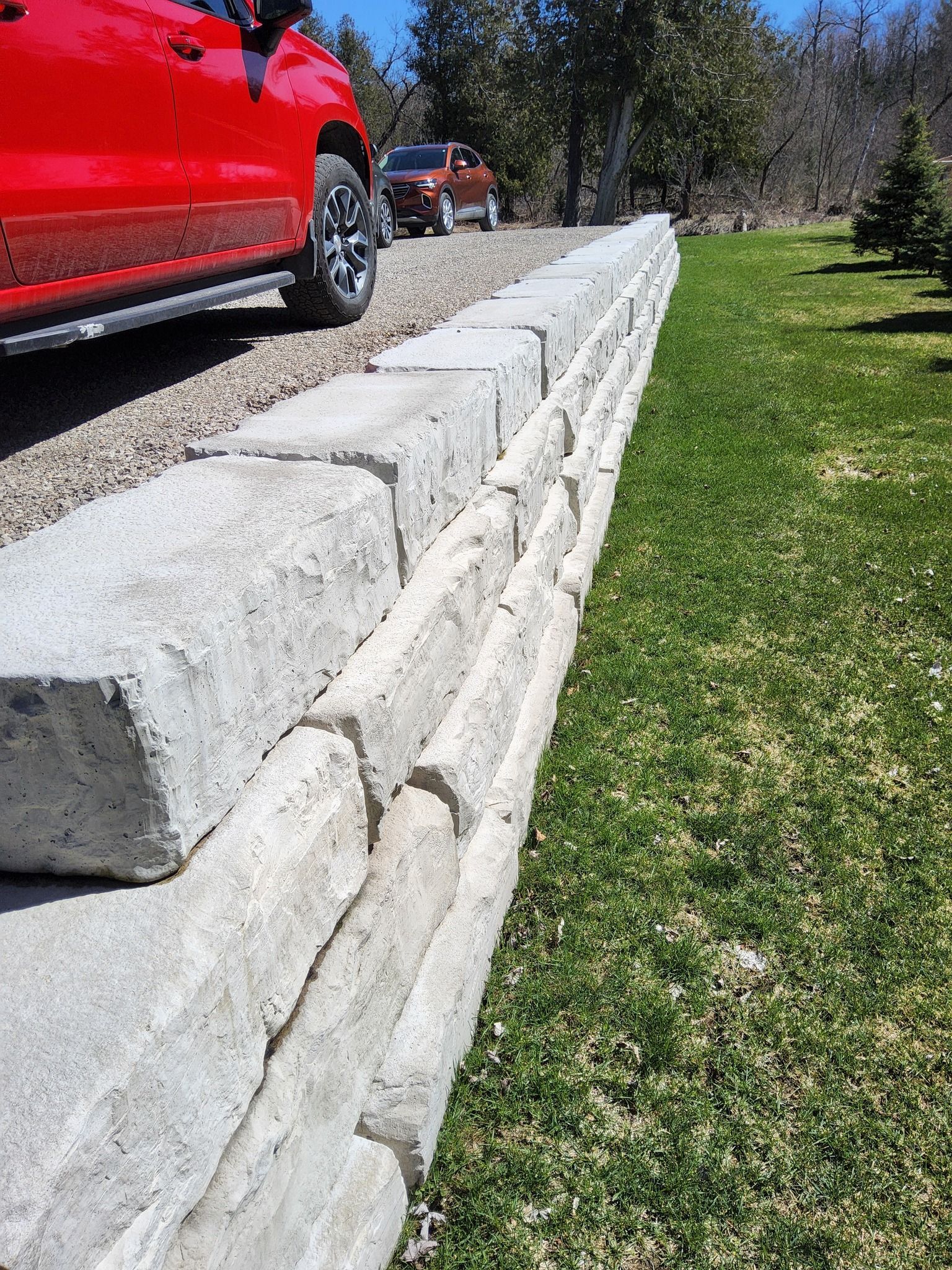 A red truck is parked next to a stone wall.