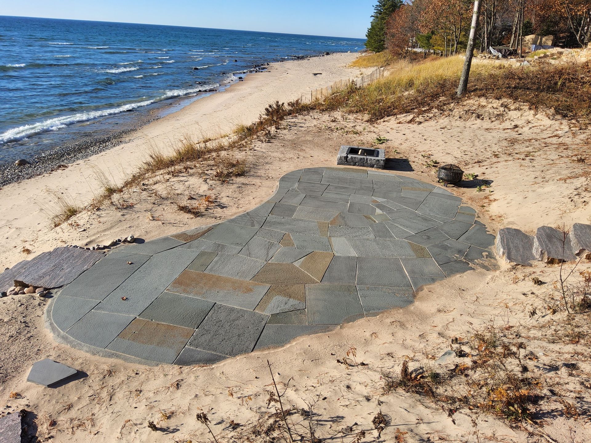 A stone patio is sitting on a sandy beach next to the ocean.