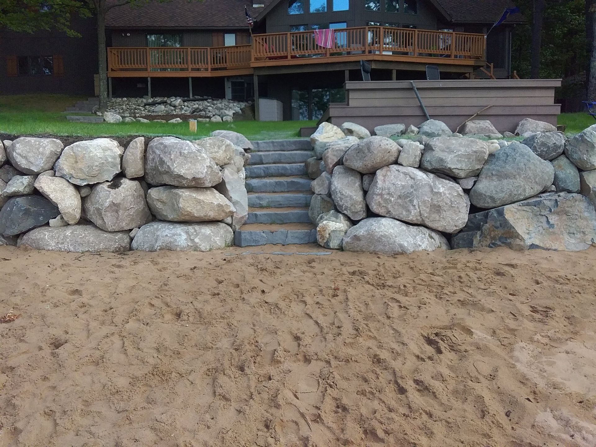A large rock wall with stairs leading up to a house