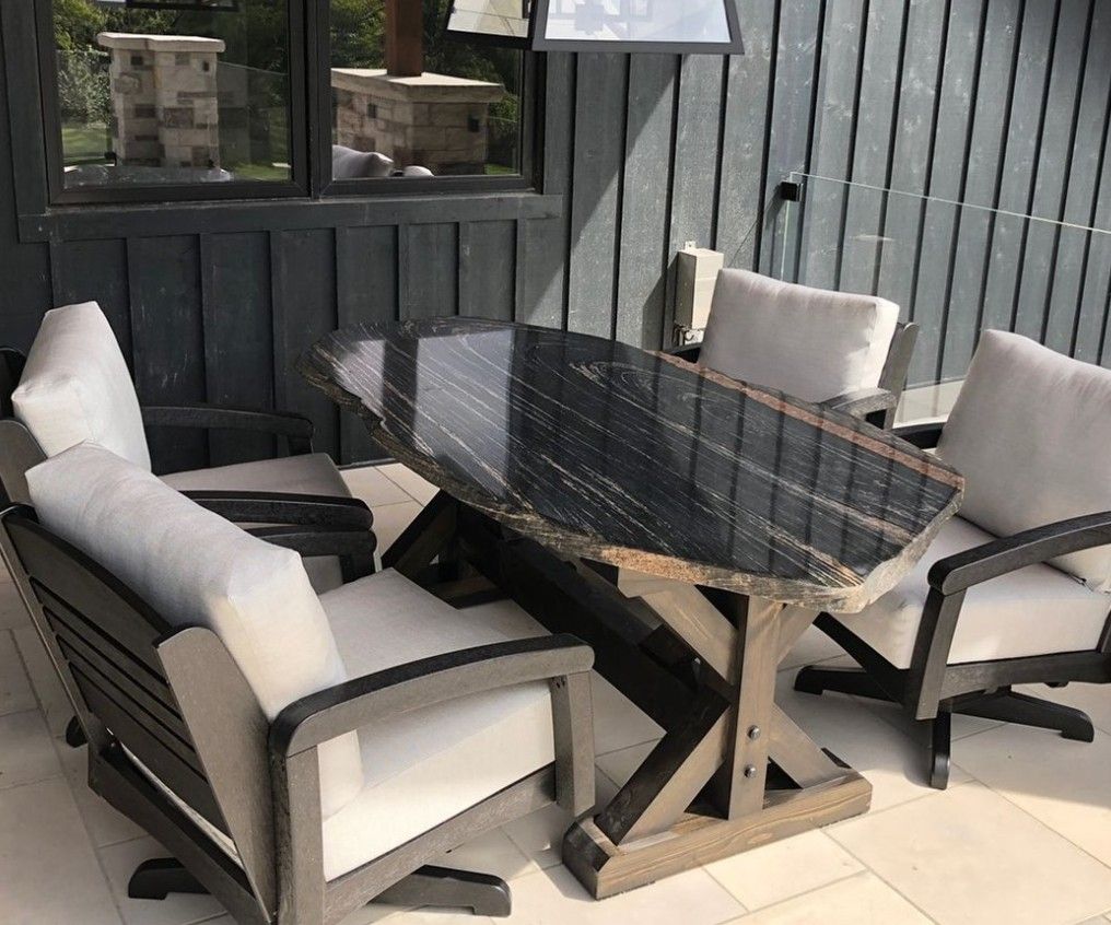 A table and chairs are sitting on a patio in front of a window.