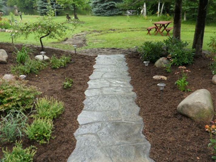 A stone walkway leading to a picnic table in the backyard