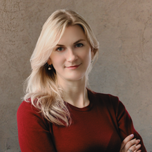 a woman in a red sweater is posing for a picture with her arms crossed .