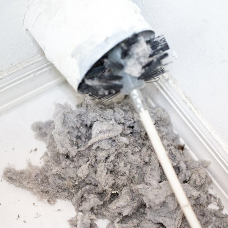 A brush being used to clean a dryer vent