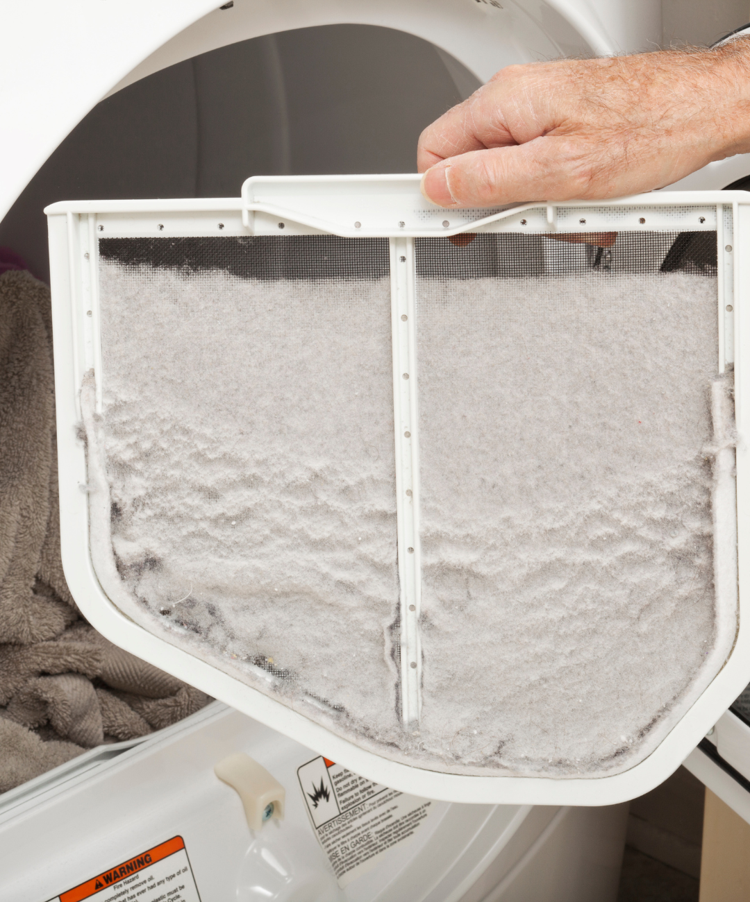 A person is removing a lint filter from a dryer