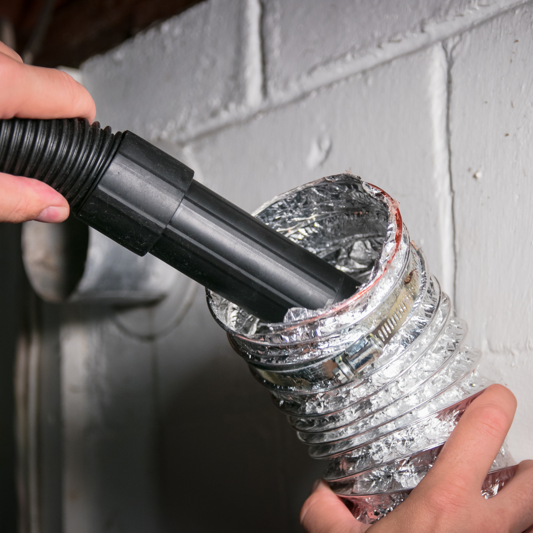 A person is cleaning a duct with a vacuum cleaner.