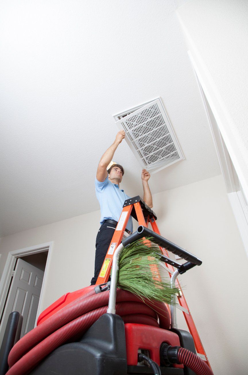 A professional air duct cleaner inspecting home air duct vent.jpg