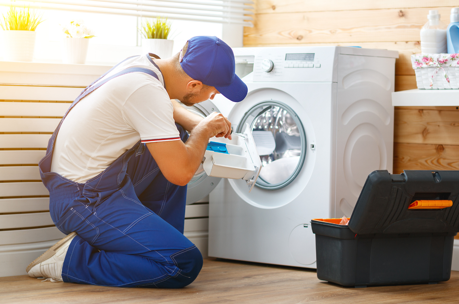 A professional cleaner wearing a denim jumper servicing a dryer
