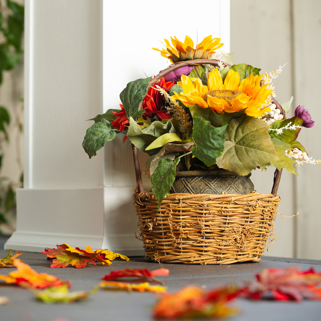 A brightly colored flower arrangements accents a porch scattered with fall leaves
