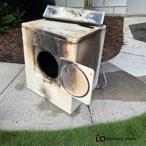 Burnt dryer placed outside near a building.