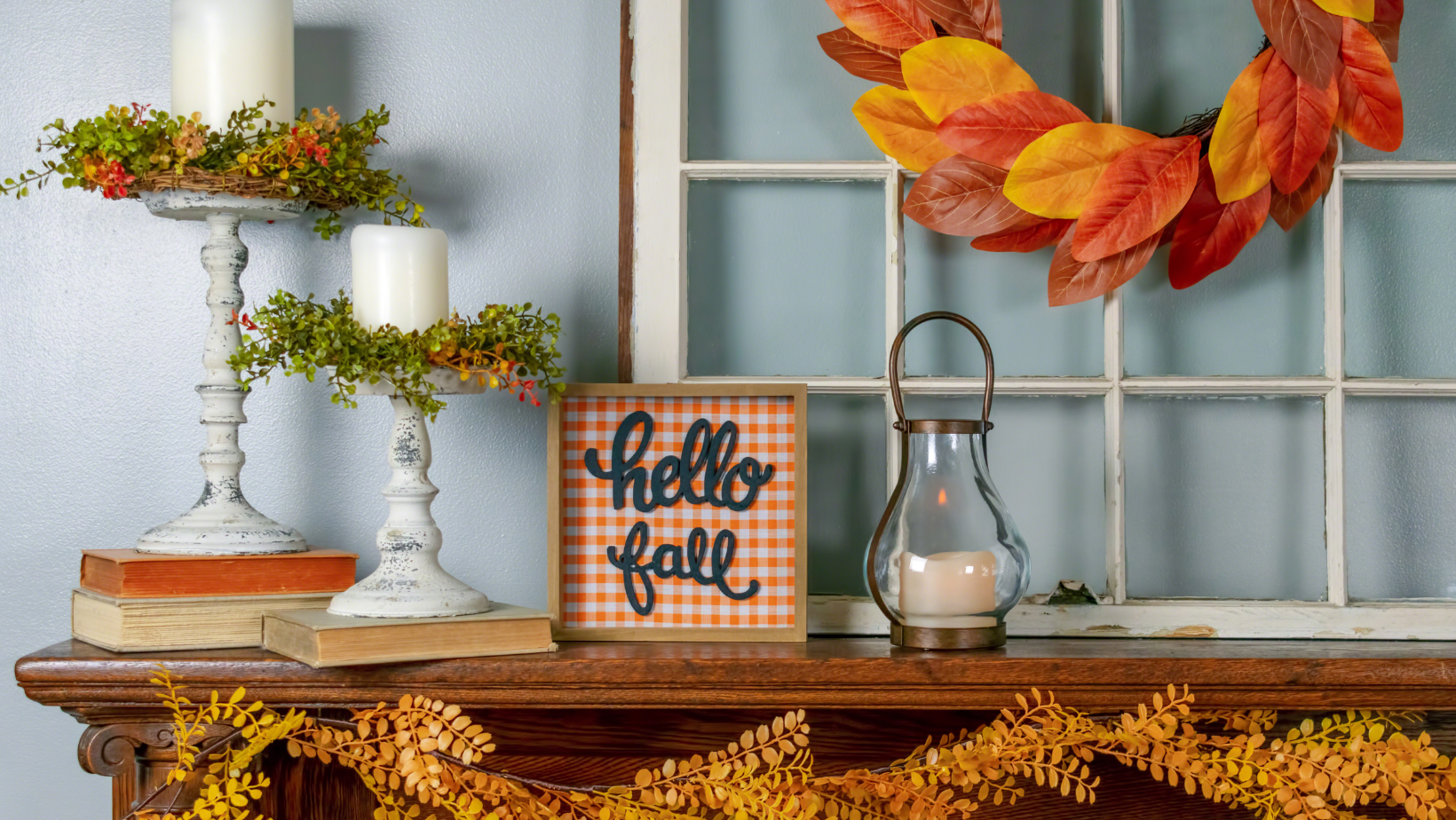 Fireplace mantle is adorned with candles, brightly colored leaves and other autumn-themed accents