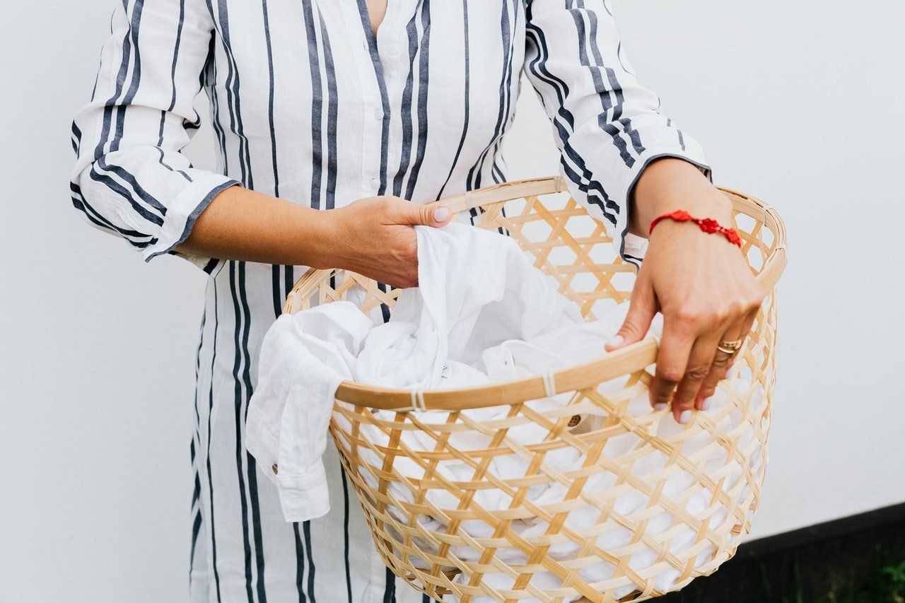 Woman holding a basket if damp clothes in a woven basket