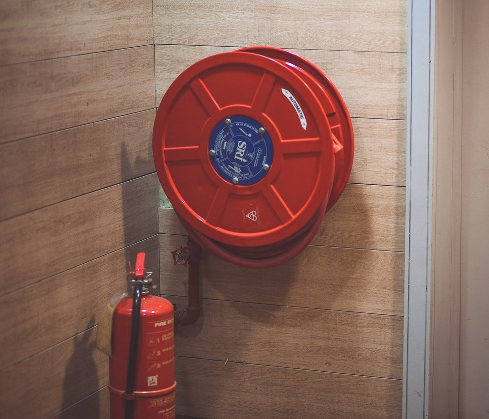 A corner with a red fire hose and a fire extinguisher