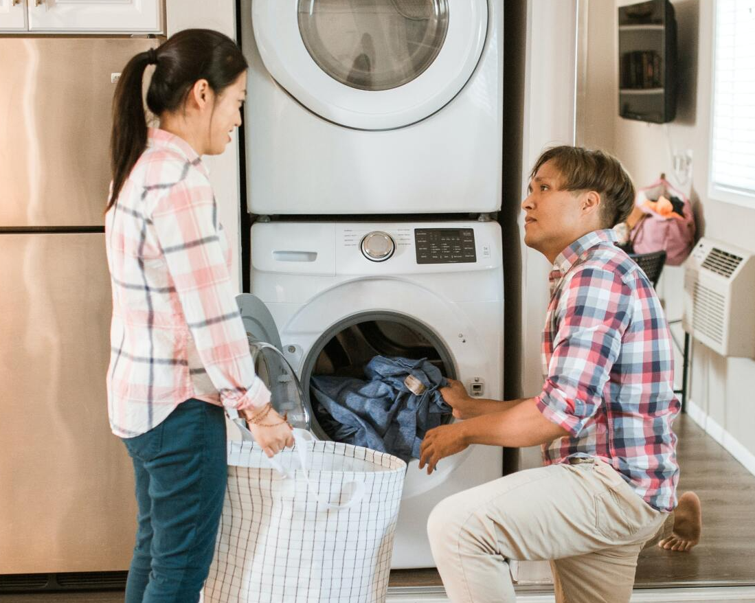 A man and a woman putting in clothes in their dryer