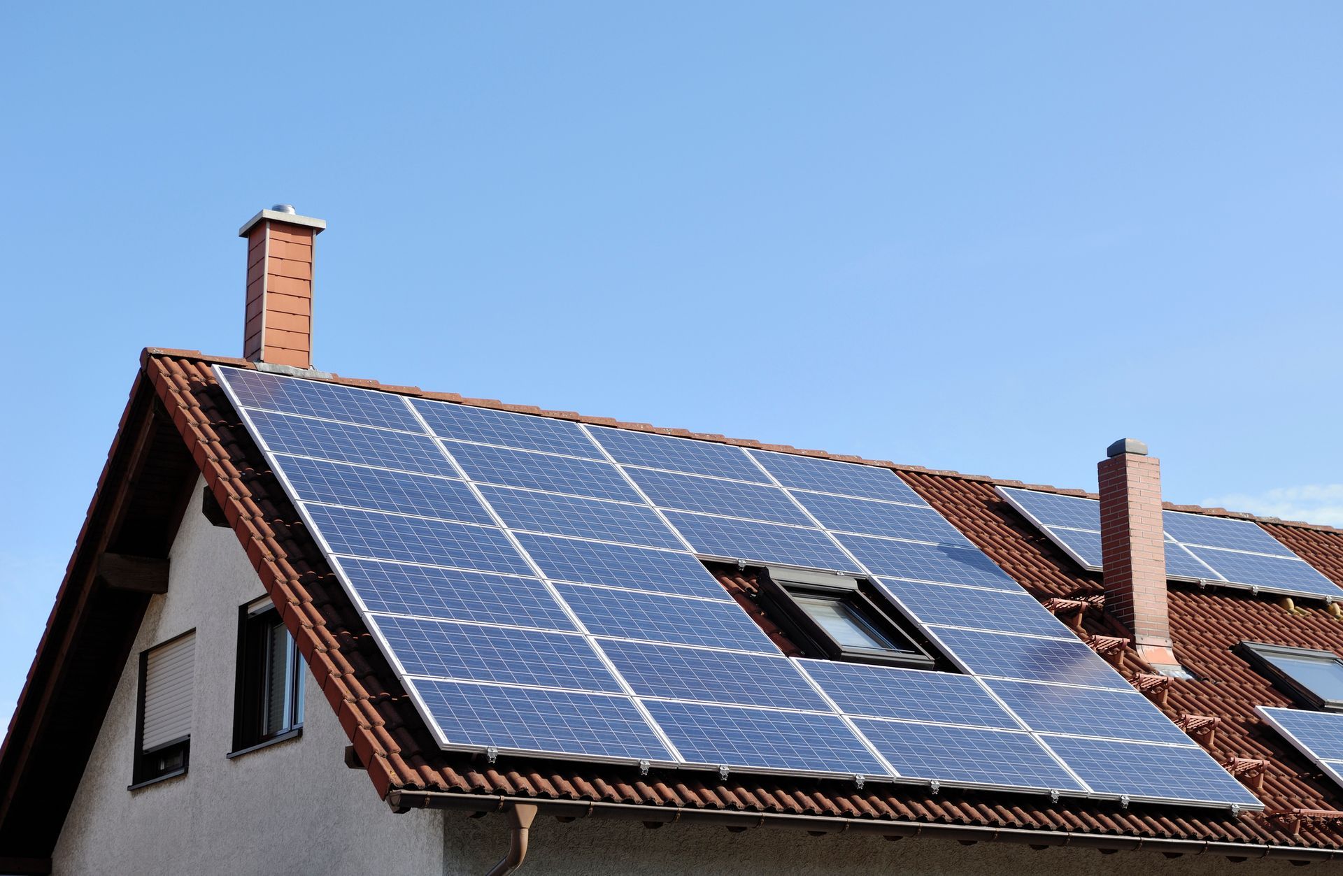 Il tetto della casa è ricoperto di pannelli solari sotto un cielo azzurro e limpido.