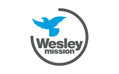 Wesley Mission logo with a blue dove above gray text inside a circular gray arc