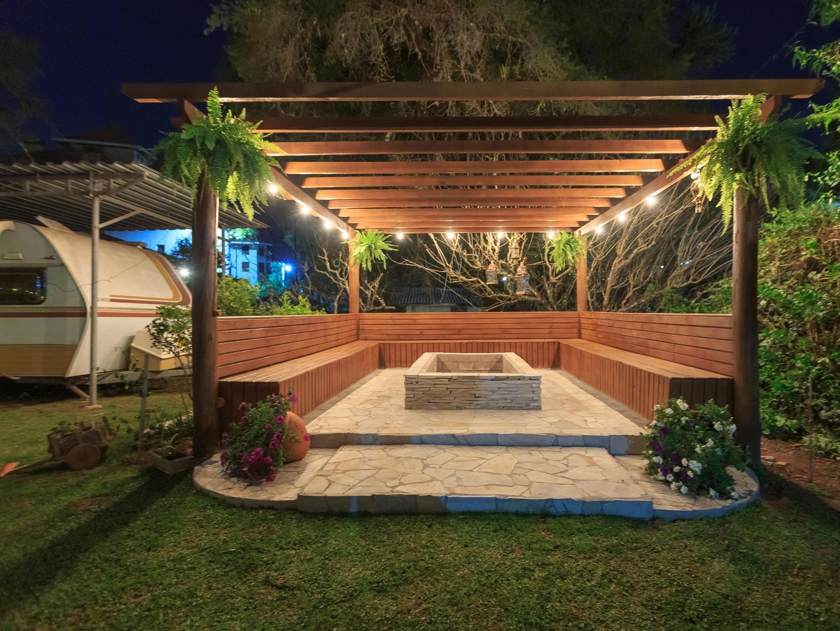 contemporary patio with stone base and pergola with lights and plants